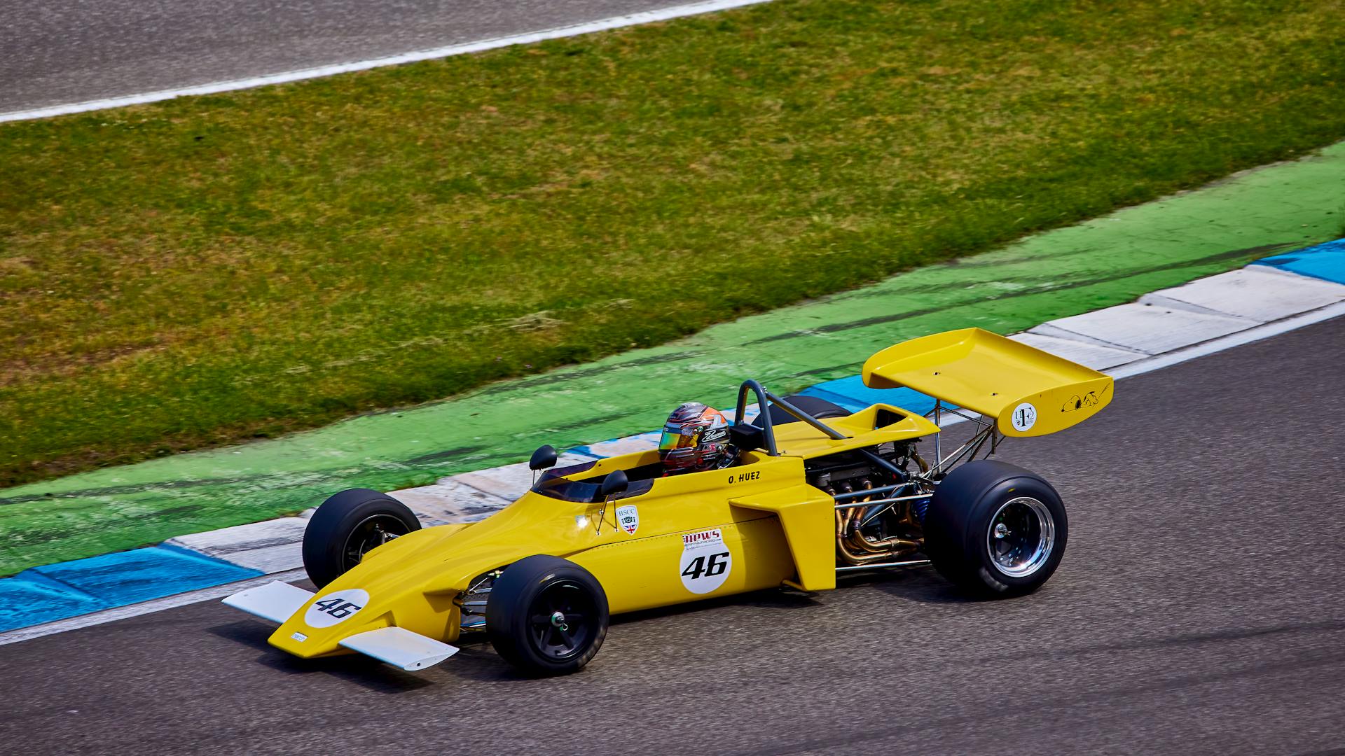 Vibrant yellow vintage race car speeding on a race track, capturing the essence of motorsport.