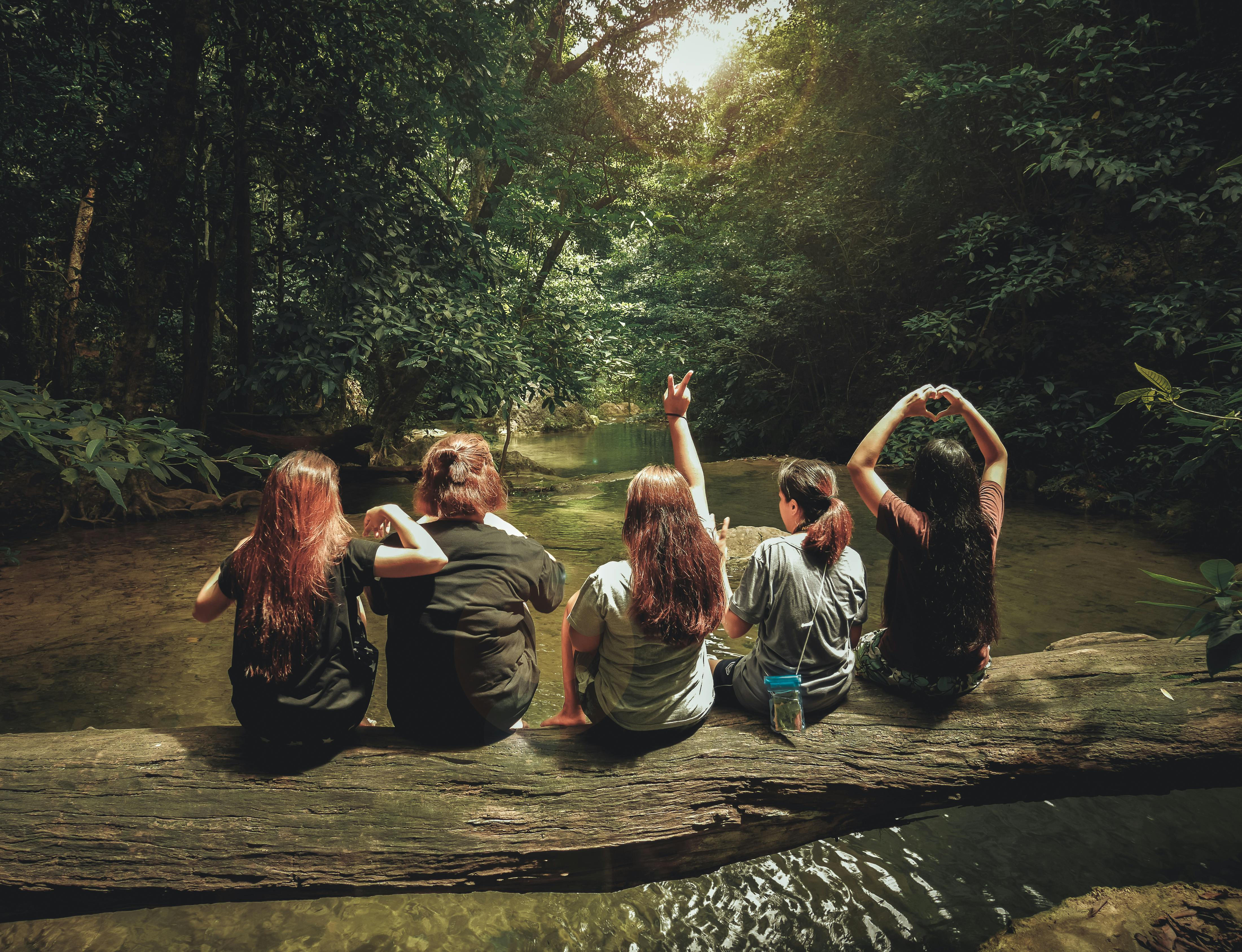 five women sitting on tree trunk