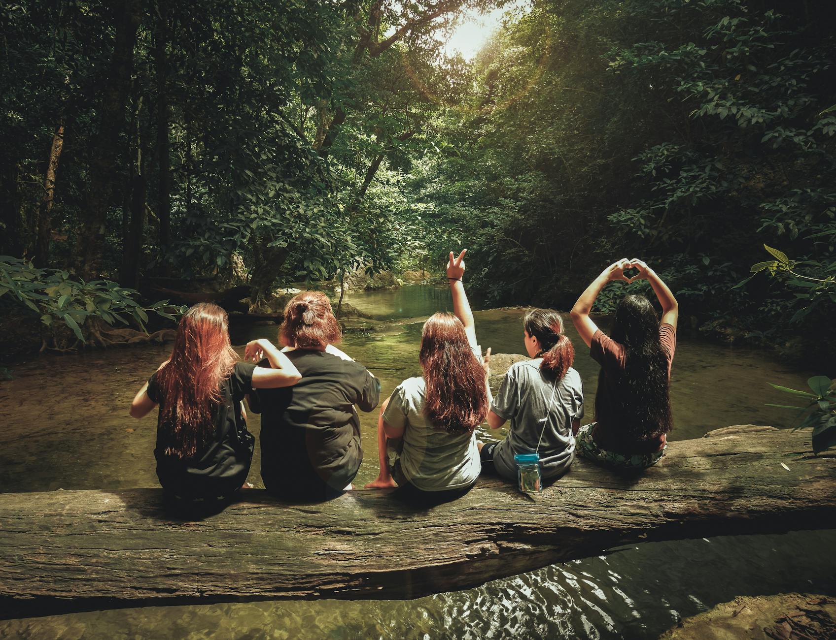 Five girls sitting on a tree trunk 