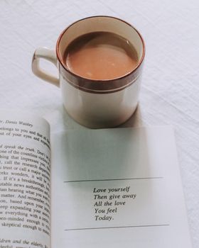A warm, inviting setup featuring a coffee mug and an open book with a motivational quote.