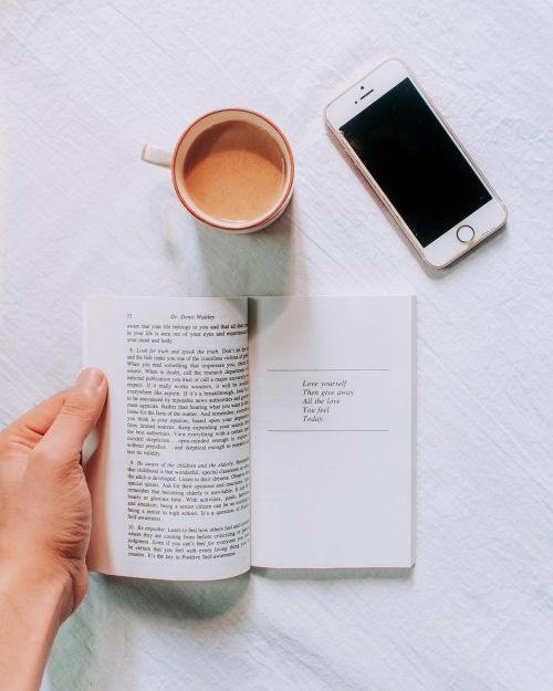 Free Top view of a cozy morning setup with a book, coffee, and smartphone. Stock Photo