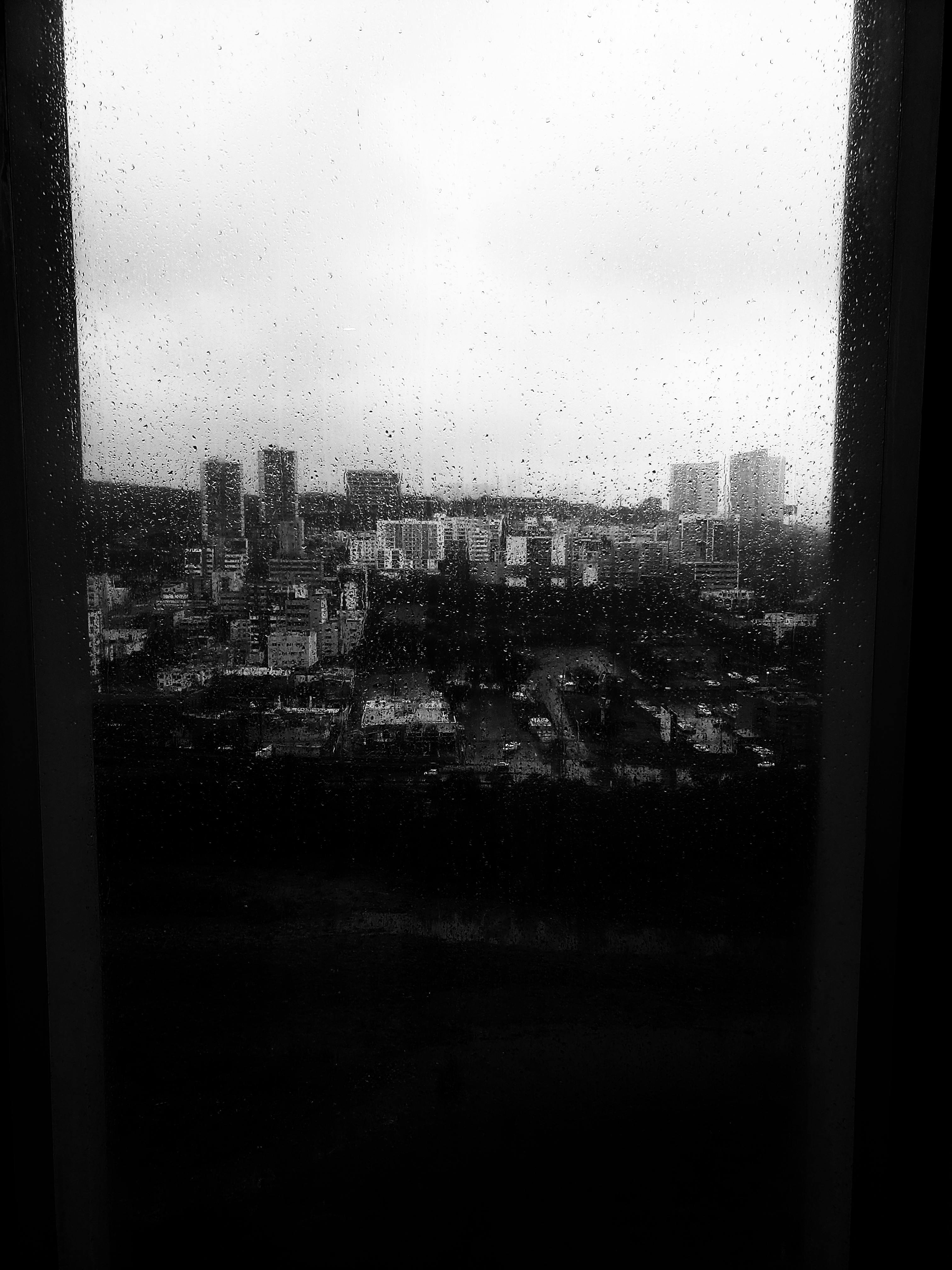 Black and white cityscape of Monterrey seen through a rain-speckled window, creating a moody urban atmosphere.