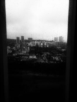 Black and white cityscape of Monterrey seen through a rain-speckled window, creating a moody urban atmosphere.