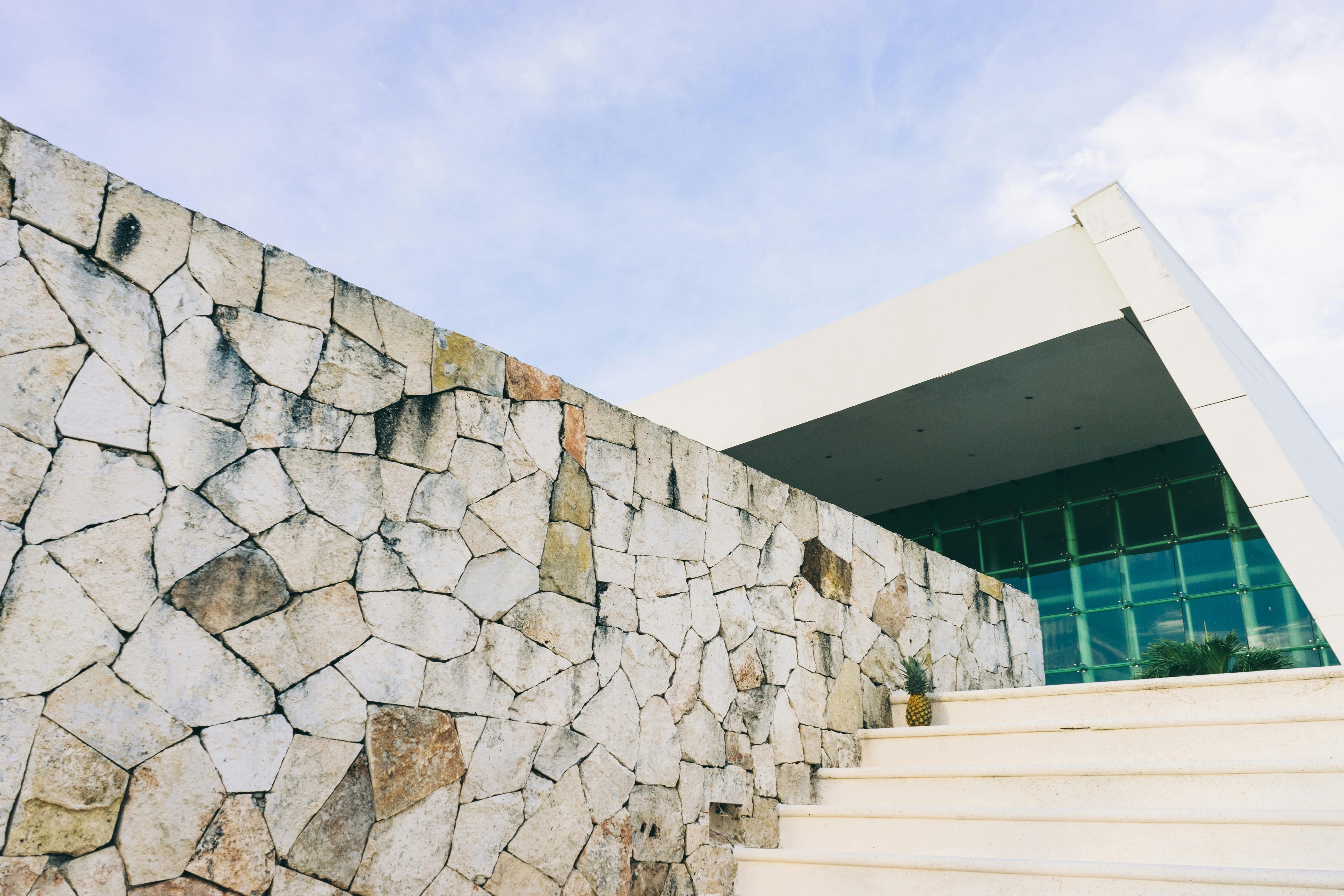 在晴朗的天空下，一座当代建筑的立面展现出石墙和棱角分明的结构