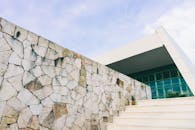 在晴朗的天空下，一座当代建筑的立面展现出石墙和棱角分明的结构