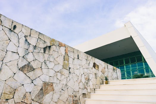 在晴朗的天空下，一座当代建筑的立面展现出石墙和棱角分明的结构