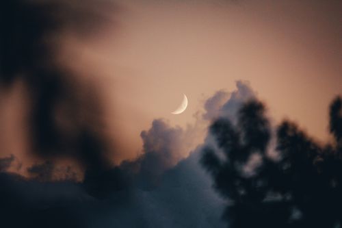 Free Ethereal crescent moon shining through dramatic clouds during twilight. Stock Photo
