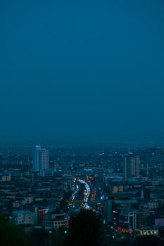 City skyline at night showcasing illuminated streets, skyscrapers, and vibrant city life under a serene sky.