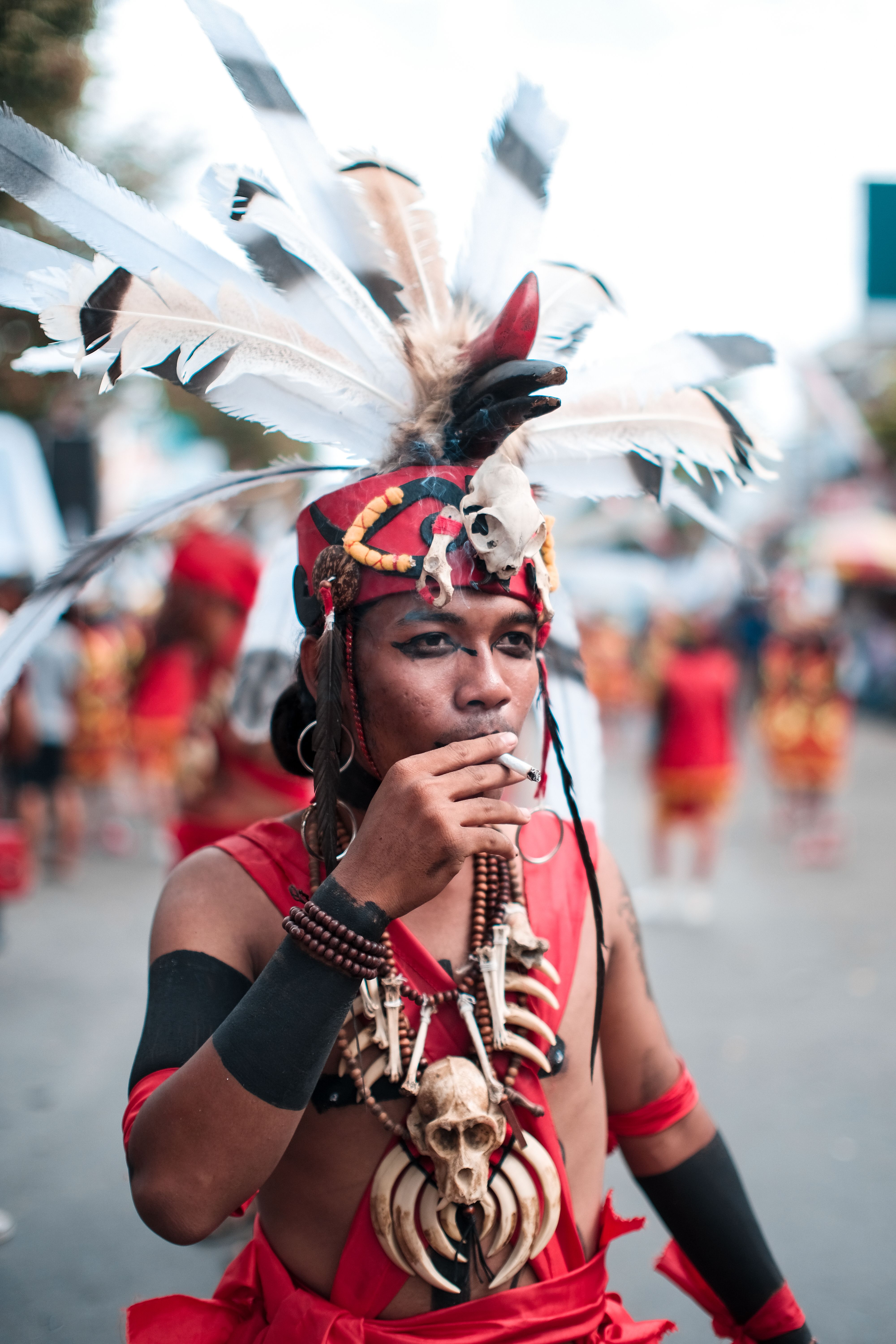 Man in vibrant traditional attire during cultural festival, wearing ornate feather headdress.