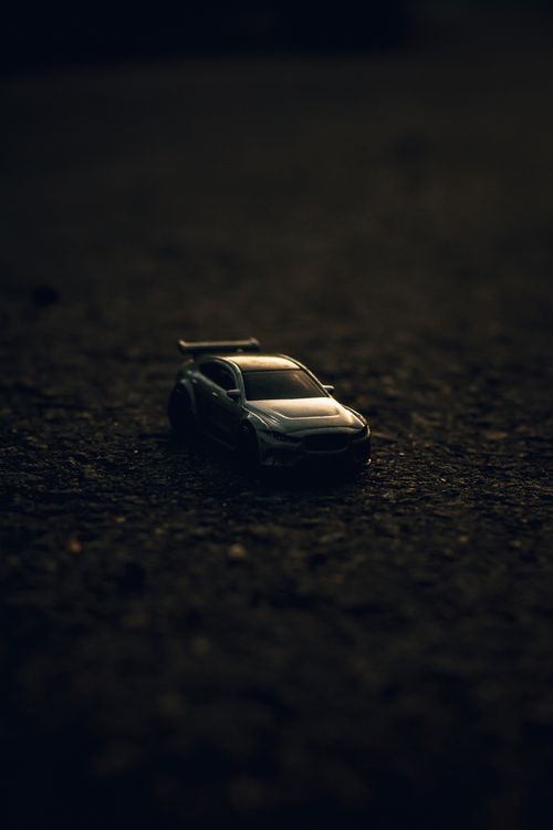 Free A dramatic close-up of a toy car on a textured dark surface with moody lighting. Stock Photo