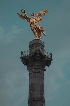A low-angle view of the Angel of Independence against a clear blue sky in Mexico City.