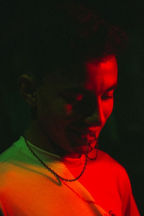 Free Artistic portrait of a person bathed in red and green light, wearing a chain necklace. Stock Photo