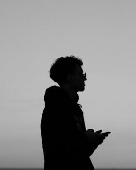 Profile silhouette of a person holding a phone in grayscale.