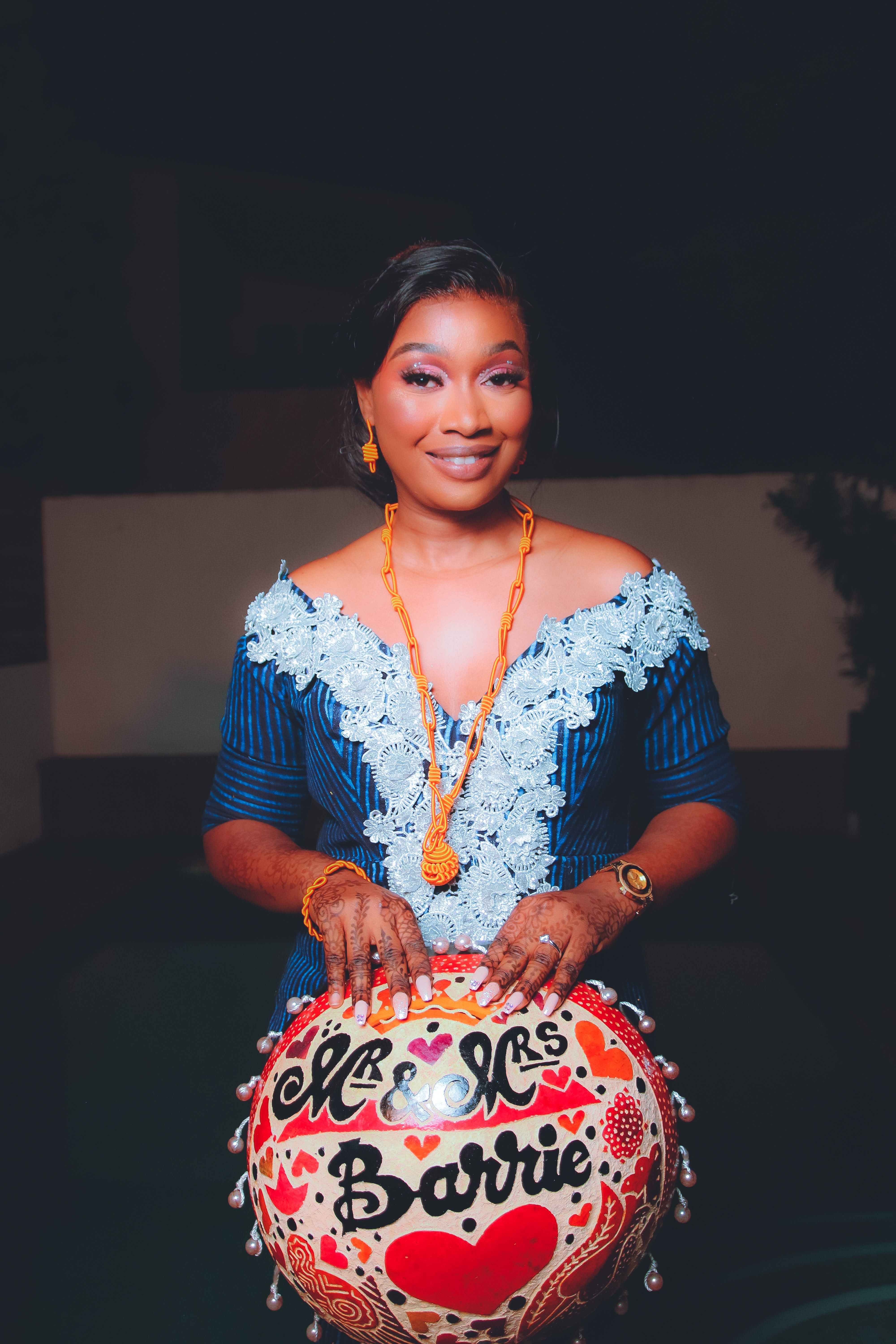 Woman posing with a decorated balloon, celebrating a special occasion. She wears elegant attire and jewelry.