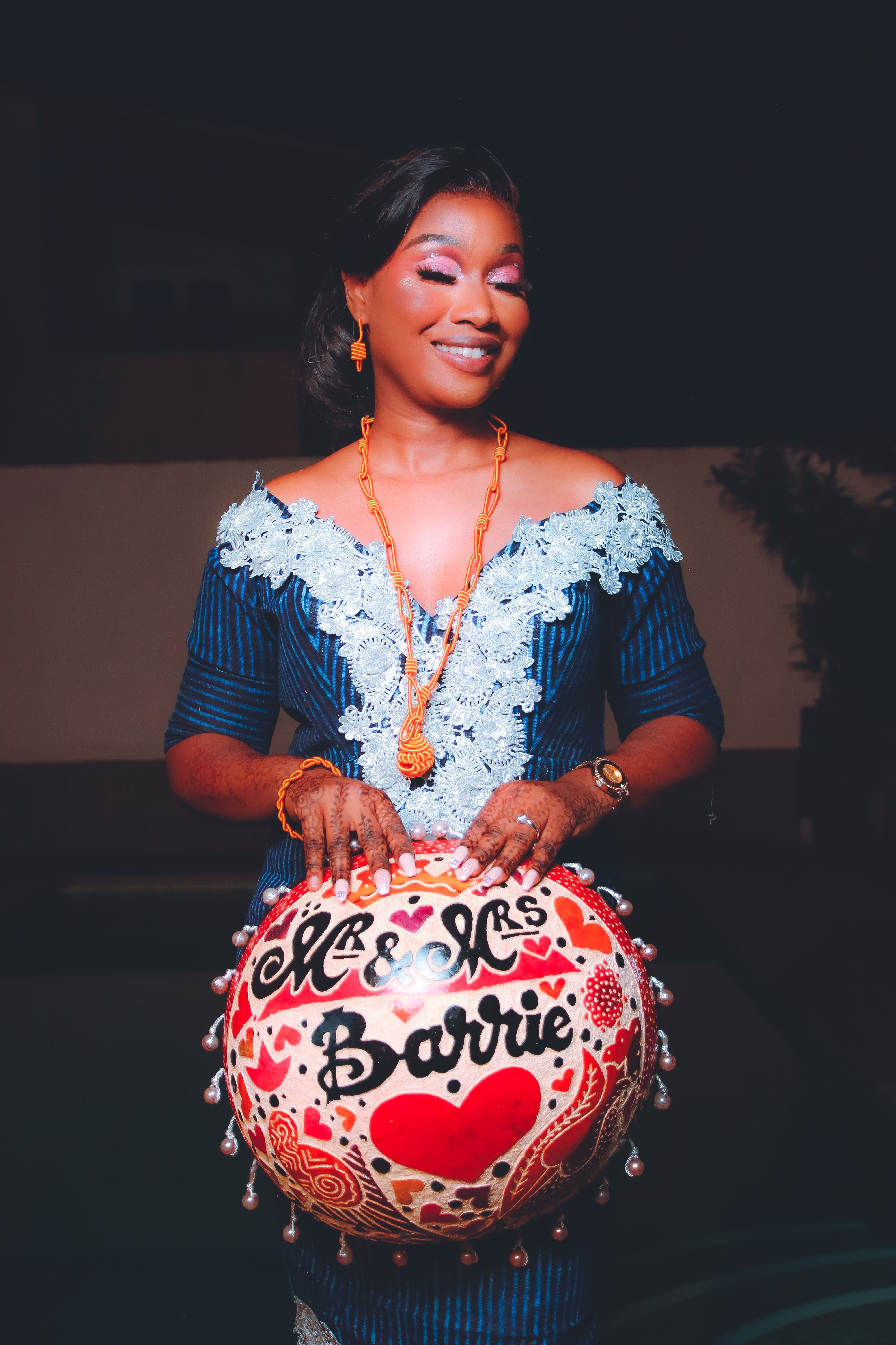 A smiling woman in traditional attire holding a vibrant decorated bowl labeled 'Mr & Mrs Barrie.'
