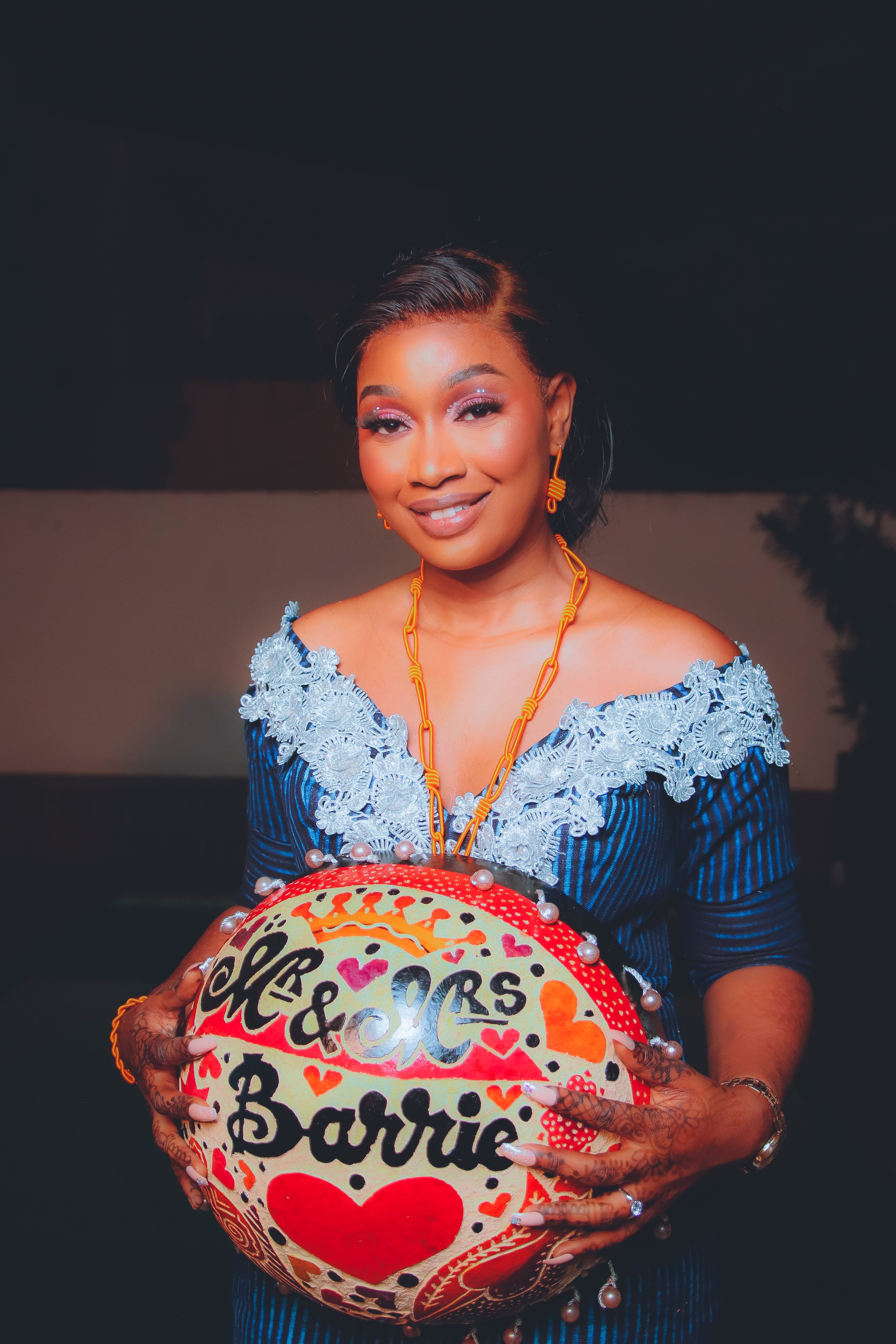Smiling woman in blue dress holding a colorful decorative ball with custom lettering.