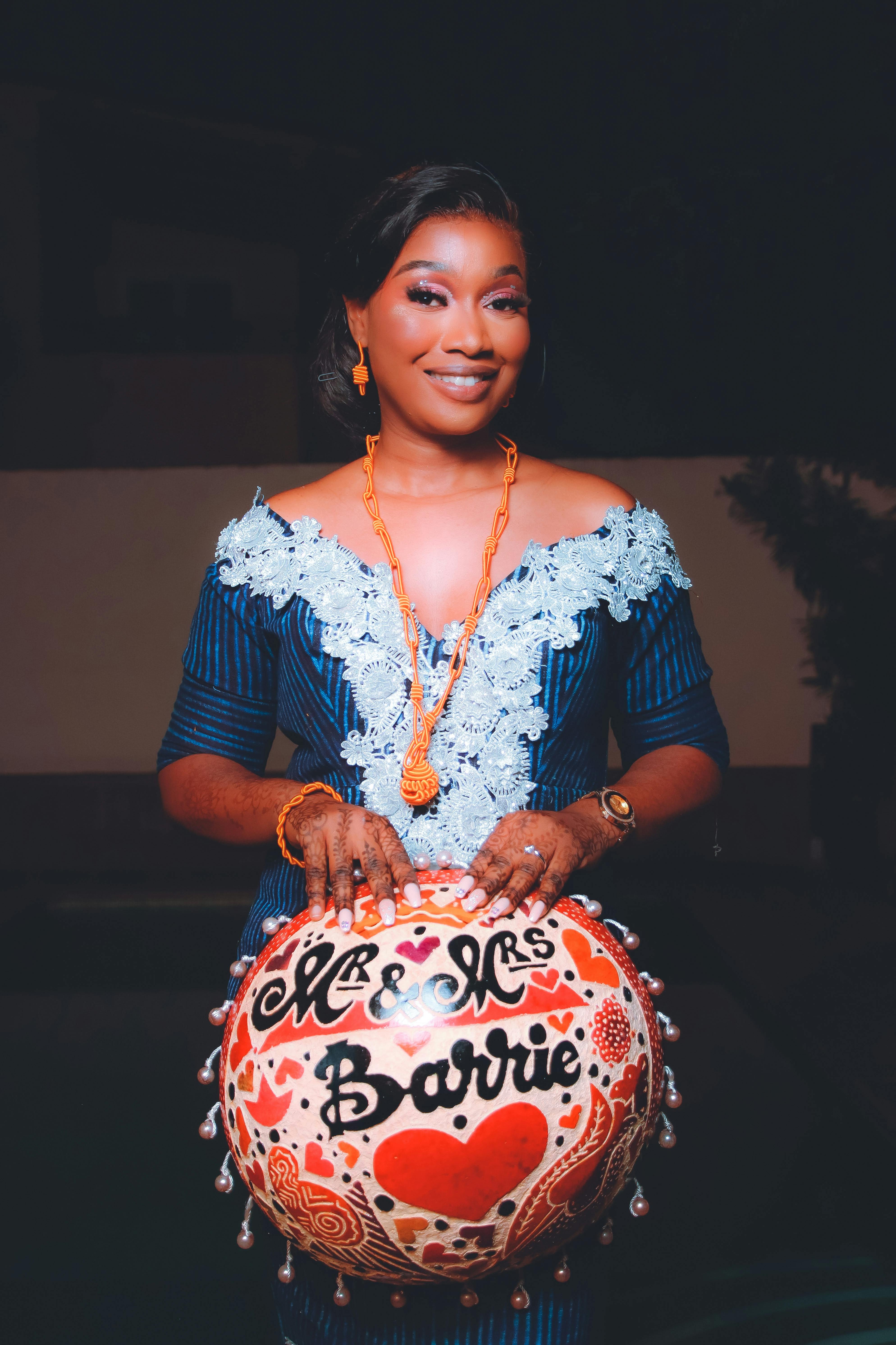 Elegant woman in blue dress holding a decorative balloon with 'Mr & Mrs Barrie' inscription, smiling.