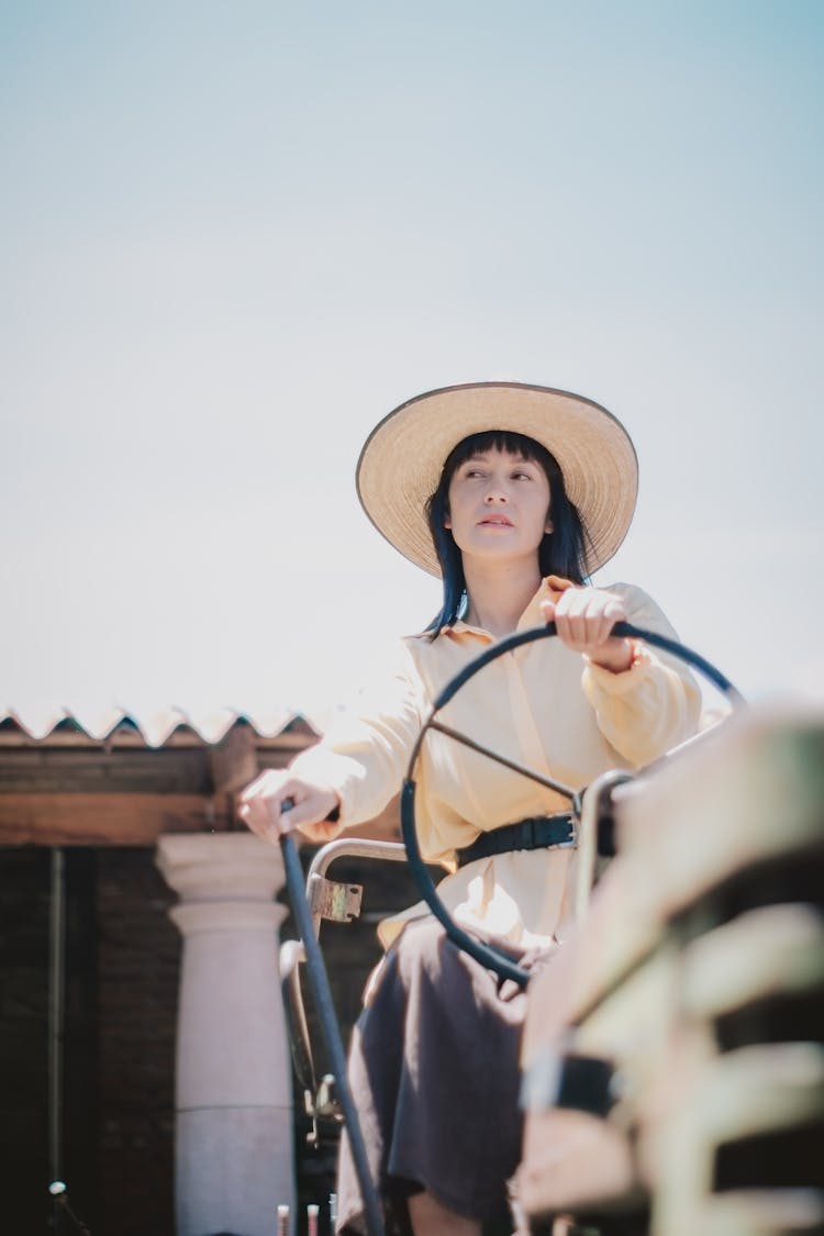 Woman In Hat Sitting And Holding Steering Wheel