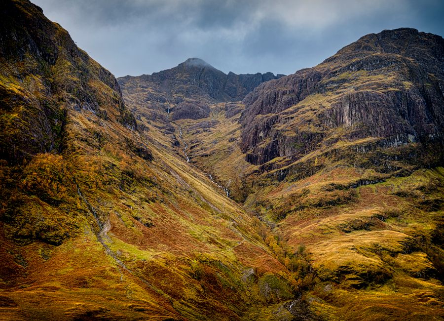 Breathtaking view of the dramatic mountains in Glencoe, Scotland, showcasing rich seasonal colors.