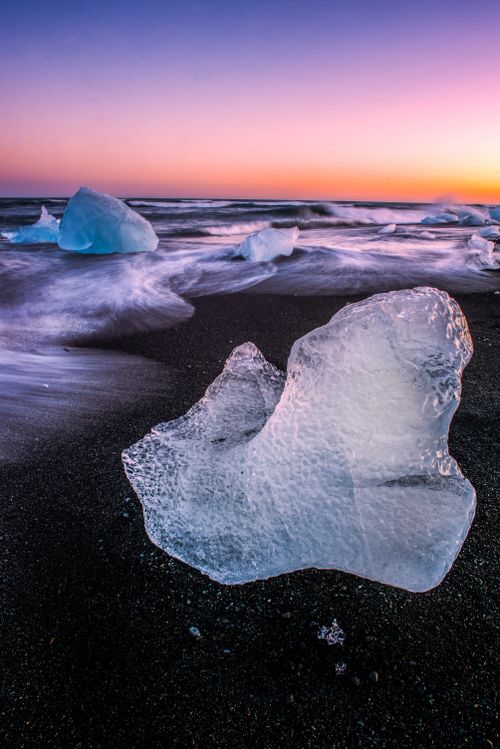 Free Beautiful icebergs on a black sand beach in Reykjavík, Iceland at twilight, creating a serene winter landscape. Stock Photo