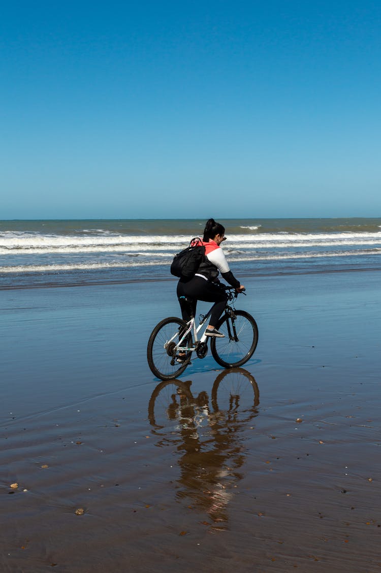 Woman Riding A Bicycle On A Beach 