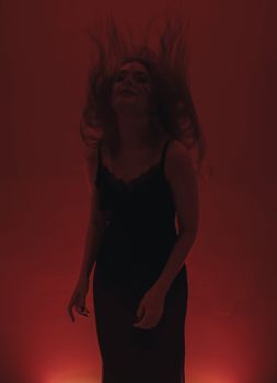 Artistic capture of a woman in motion against a red background, featuring dramatic lighting and a black dress.