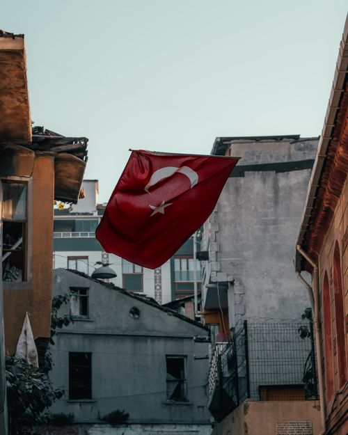 Free Turkish flag waving amidst urban buildings in atmospheric street view. Stock Photo