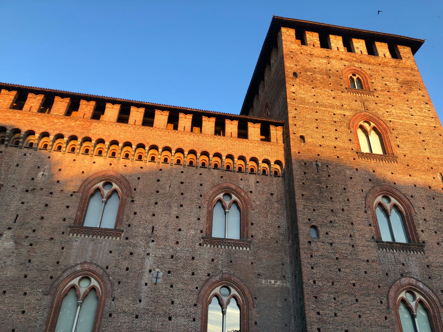 Medieval Visconti Castle facade illuminated by sunset glow in Pavia, Lombardy.