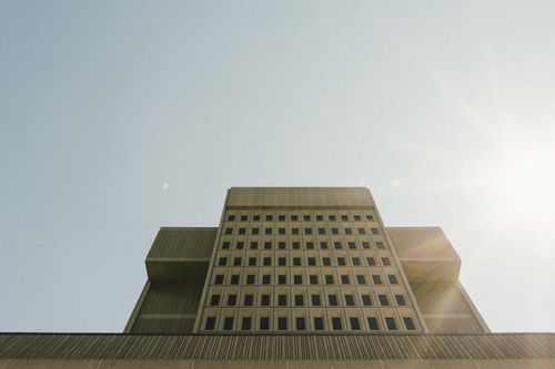 Free Low angle view of a modern urban skyscraper with a sun flare and minimalistic architecture. Stock Photo