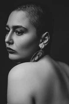A dramatic black and white portrait featuring a woman with short hair and a bold earring.