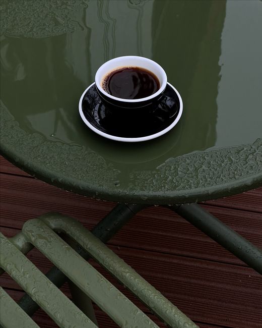 Cup of coffee on a wet table after rain. Perfect for cozy moments.