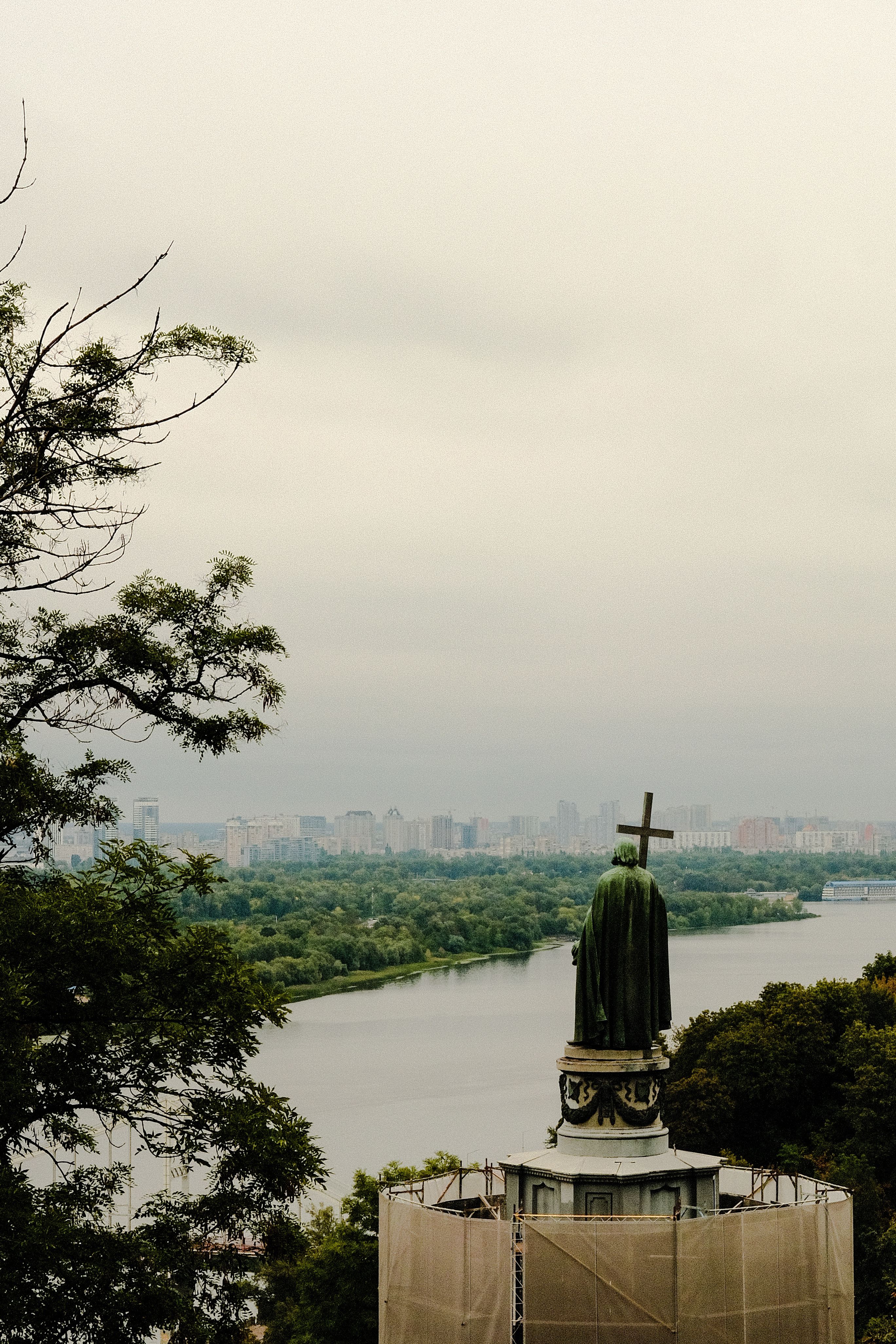 St. Volodymyr statue overlooking the Dnieper River with cityscape in background on an overcast day.