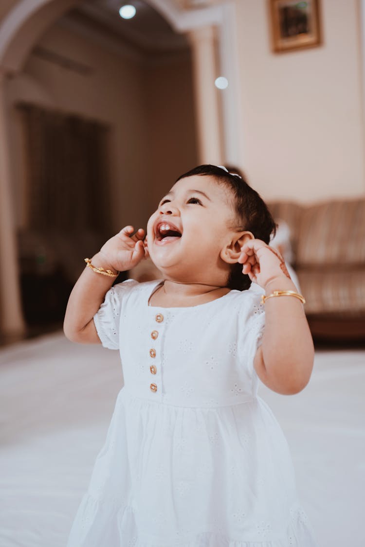 Toddler In White Dress Looking Up