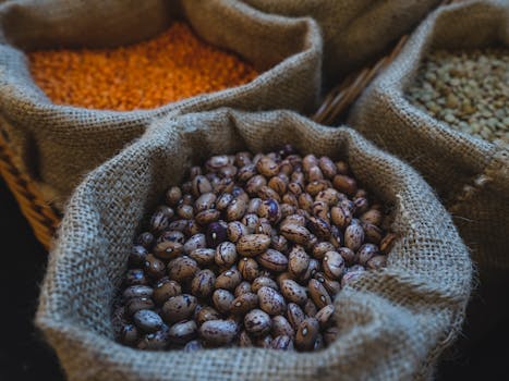 Close-up of pinto beans, lentils, and other grains in burlap sacks in a market setting.