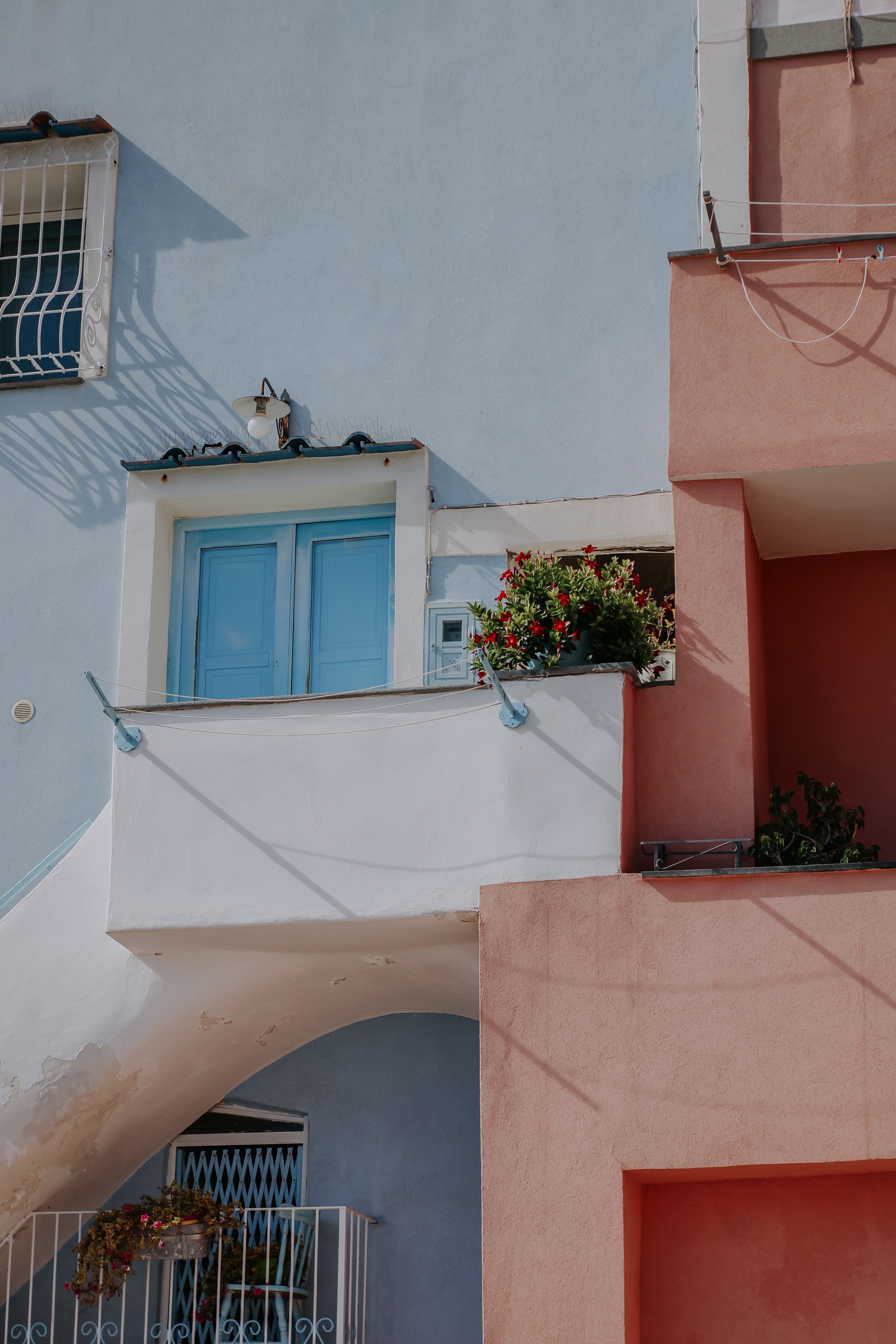 Pastel-colored residential building with balconies and plants, featuring Mediterranean design elements.
