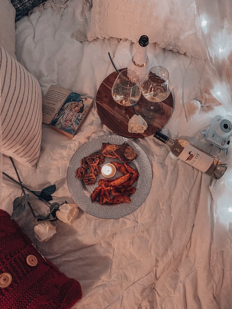 Bottles And Wax Candle Near Book On Bedclothes