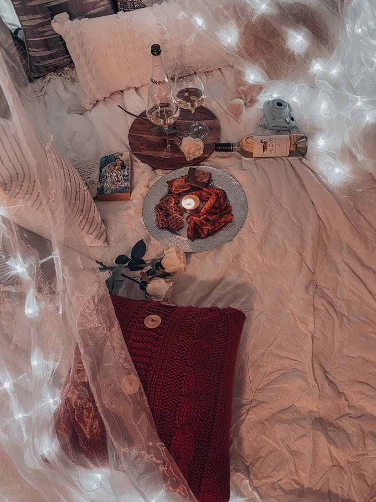 High Angle View Of A Decorated Bed With Snacks, Alcohol And White Roses