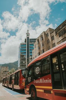 TransMilenio buses on urban streets of Bogotá, capturing city life on a sunny day.