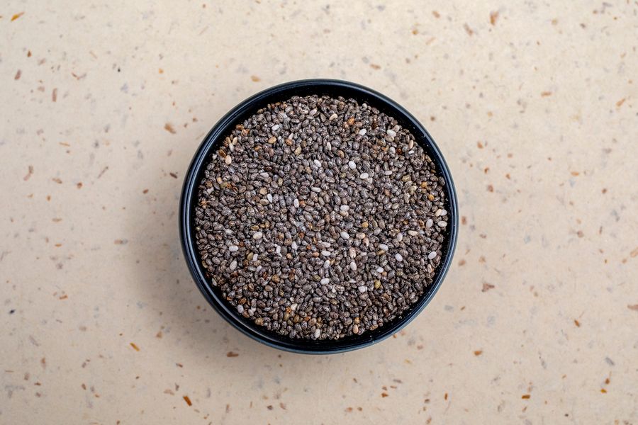 Chia seeds in a dark bowl on a neutral surface
