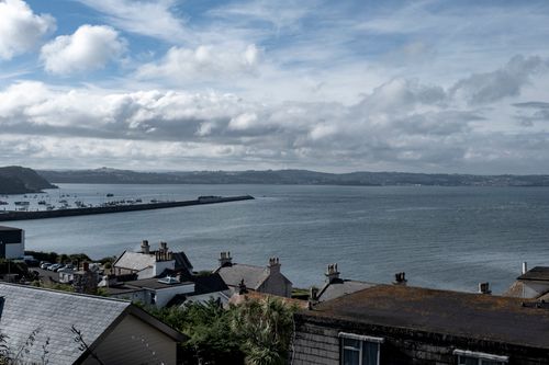 Free Aerial view of coastal houses by a harbor with a backdrop of the sea and clouds. Stock Photo
