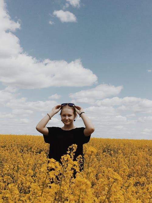 Free Blond Girl Standing in Yellow Canola Field Stock Photo