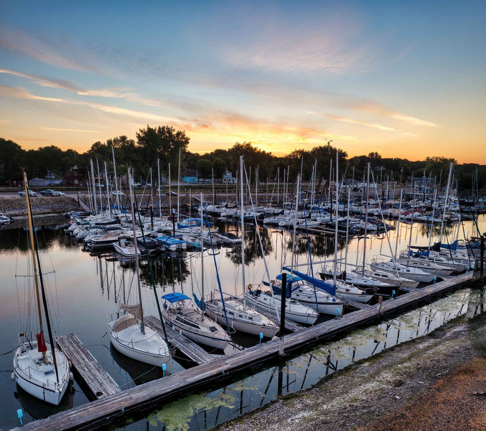 A serene view of sailboats docked at Pepin Marina in Wisconsin during twilight with a relaxing sunset.