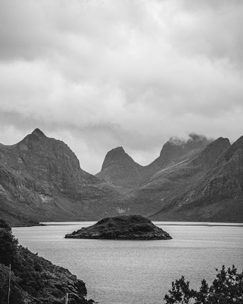 Grayscale Photo of Mountain Near Body of Water