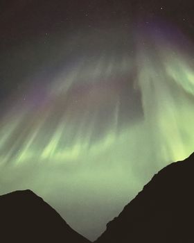 Captivating aurora display above the mountains in Nordland, Norway. Ideal for nature and astrophotography enthusiasts.