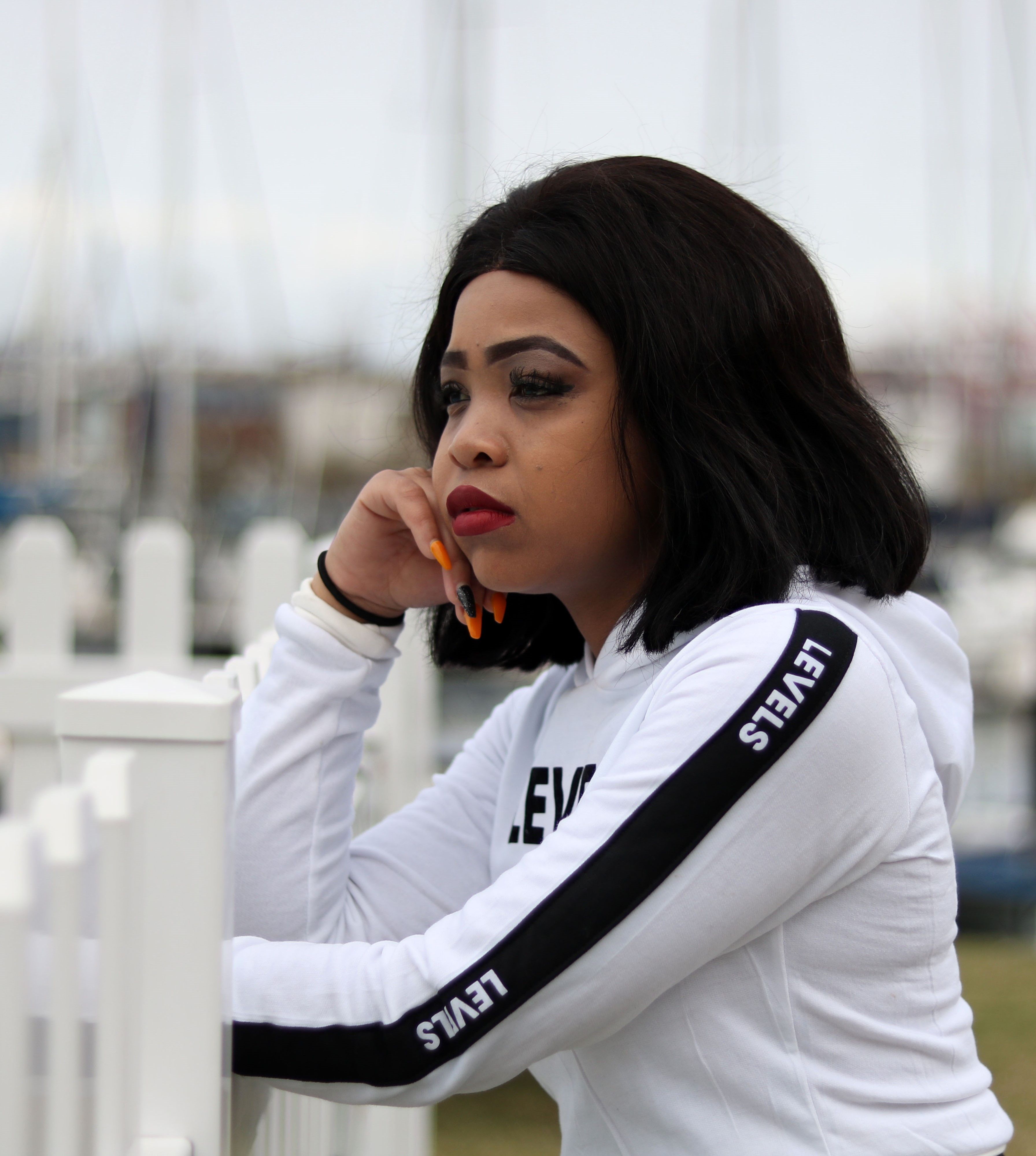 A woman leans thoughtfully against a fence by the marina in Durban, South Africa.