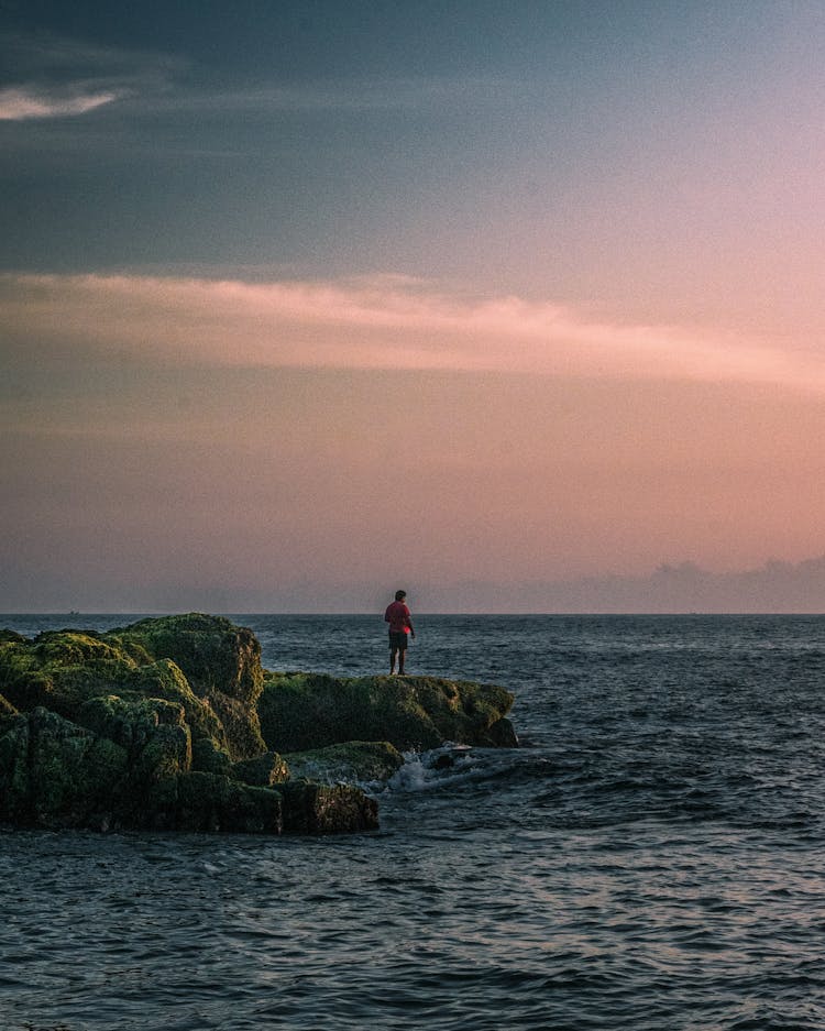 Man Contemplating Seascape On A Cliff At Sunrise