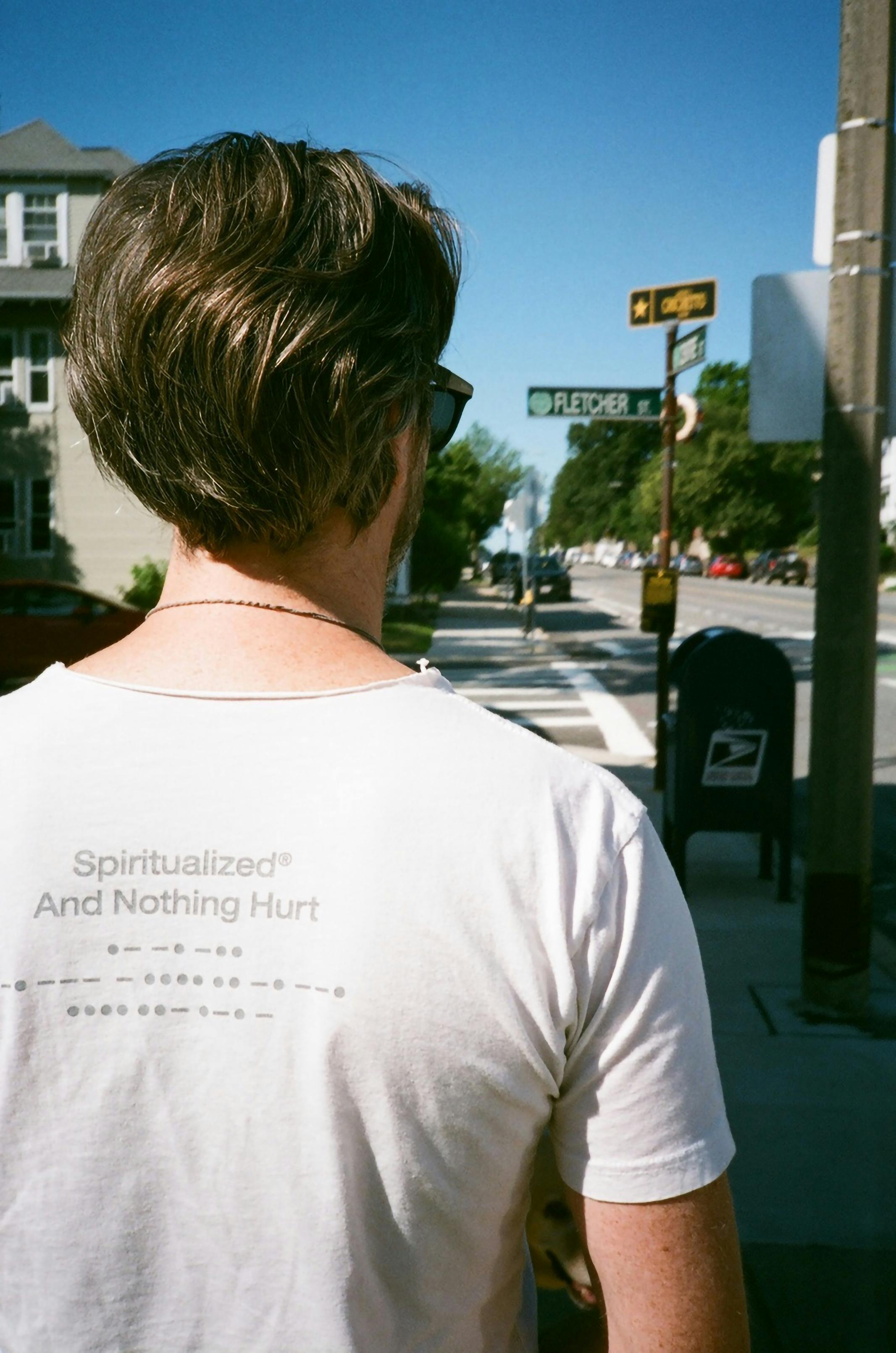 Free Back view of a man walking on a city street with a white shirt and sunglasses. Stock Photo