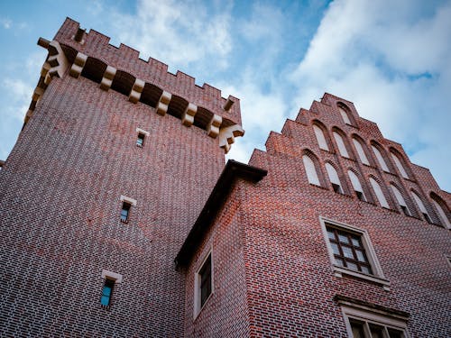 A Low Angle Shot of a Brick Building Under the Blue Sky and White Clouds