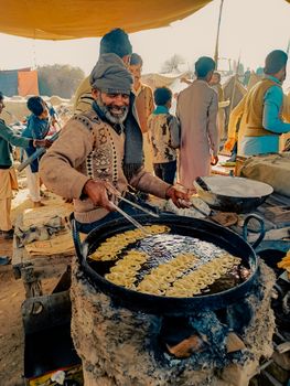 A street vendor fries traditional snacks in a bustling market setting, capturing cultural vibrancy.