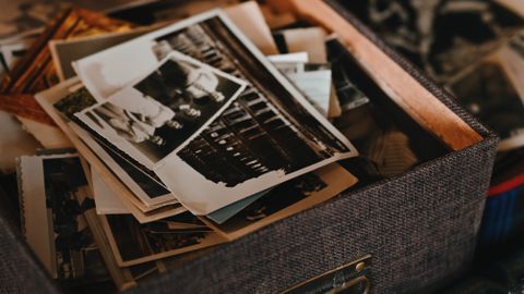 A collection of vintage photographs in a textured box, capturing old memories.